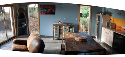 Montage panoramique de la pièce à vivre. De gauche à droite : le coin salon, la baie vitrée, la table à manger, la cuisine.